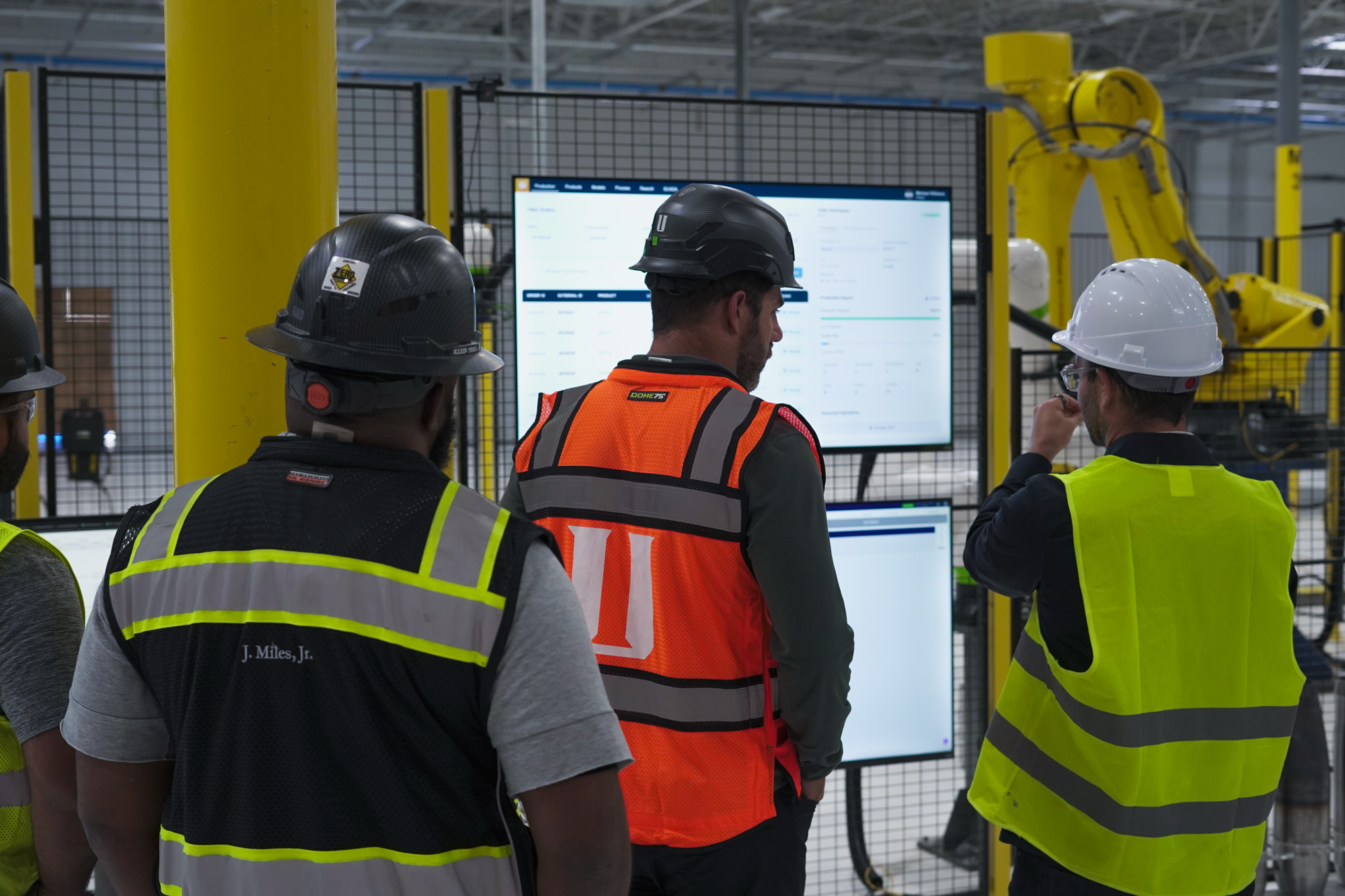 Operators at a workstation reviewing live production dashboards.